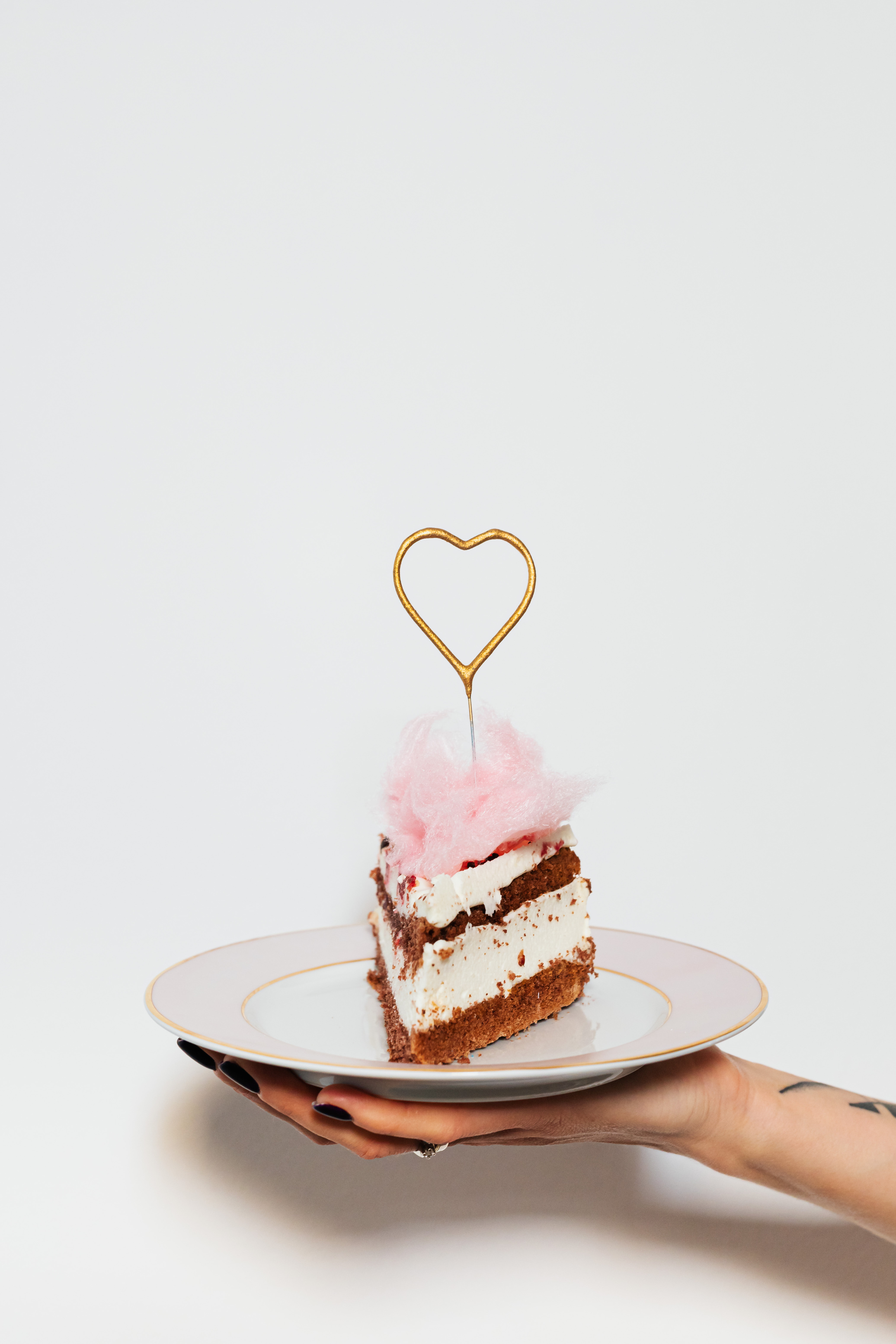 Person Holding a Plate with a Slice of Cake